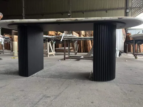 white stone dining table, with twin supporting bases and fine veining, in a workshop