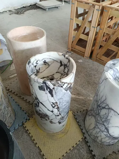white stone sink, with a form carved from solid stone and bold veining, in a workshop