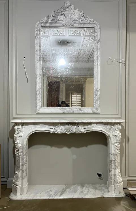 White Volakas marble fireplace surround, with an arched opening and fine veining, against a pale background