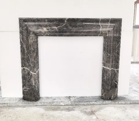 White Volakas marble fireplace surround, with fine veining and a reflective finish, against a pale background