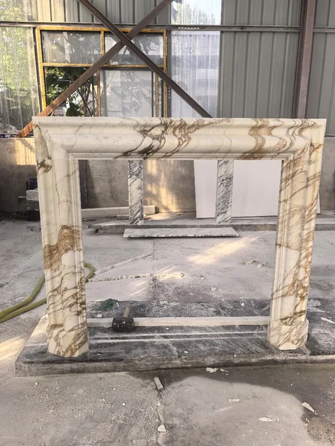 White Volakas marble fireplace surround, with bold veining and a reflective finish, in a workshop