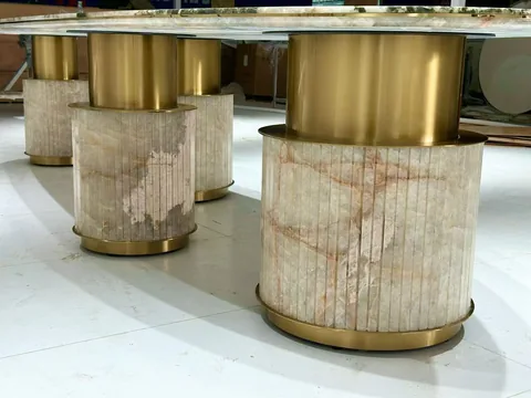 cream-beige stone dining table, with linear travertine grain and a reflective finish, in a workshop
