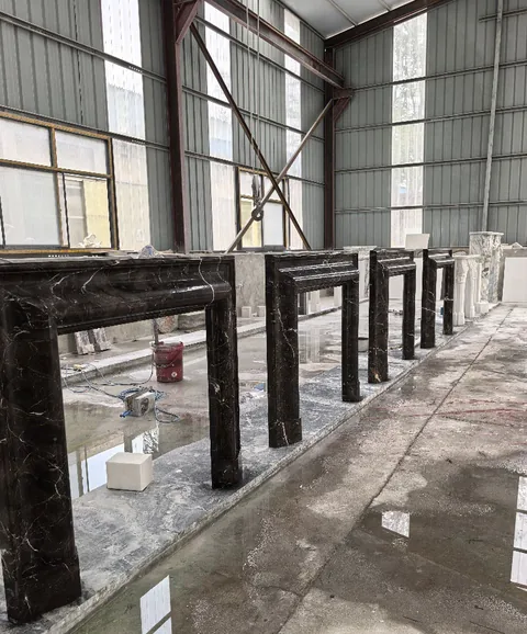 White Volakas marble fireplace surround, with stepped tiers and bold veining, in a workshop