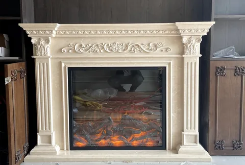 White Volakas marble fireplace surround, with carved scrollwork and fine veining, against a dark background
