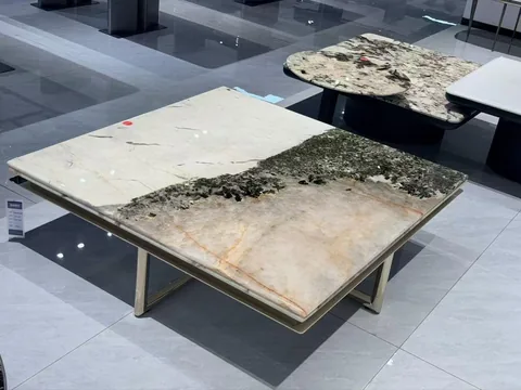 cream-beige stone coffee table, with cloudy mottling and a reflective finish, in a showroom