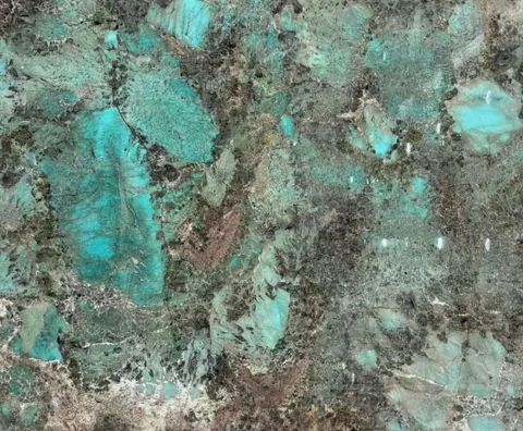 green stone slab, with a single full slab and angular breccia fragments, in a close surface view