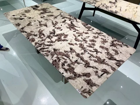 cream-beige stone dining table, with a rectangular top and angular breccia fragments, in a showroom
