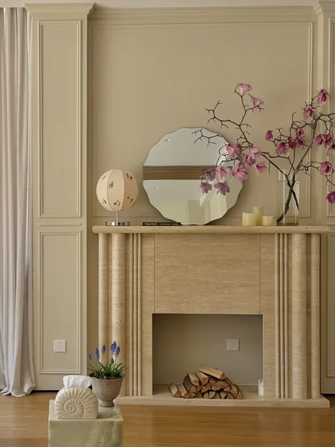 cream-beige stone fireplace surround, with a straight recessed opening and linear travertine grain, in a furnished room