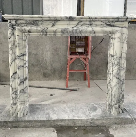 White Volakas marble fireplace surround, with bold veining and a reflective finish, in a workshop