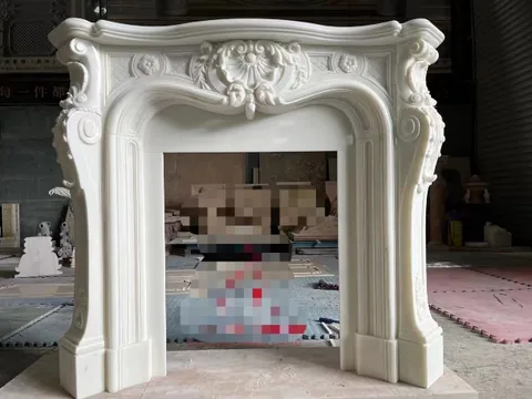 White Volakas marble fireplace surround, with an arched opening and a plain surface, in a workshop