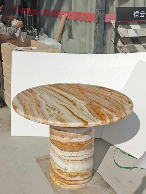 cream-beige stone dining table, with banded onyx-like striping and a reflective finish, in a showroom