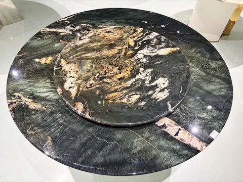 black stone dining table, with a round top and bold veining, in a showroom