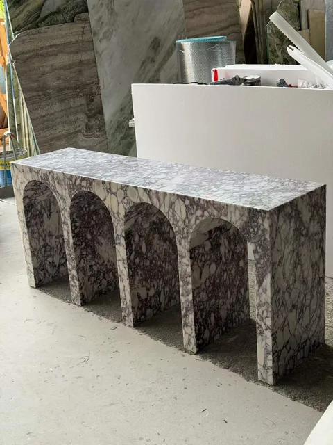 white stone bench, with angular breccia fragments and a reflective finish, in a workshop