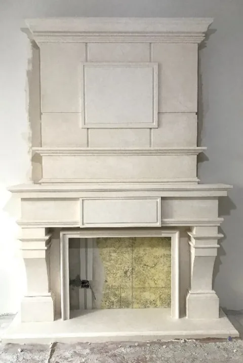 White Volakas marble fireplace surround, with a raised overmantel and a plain surface, in a workshop