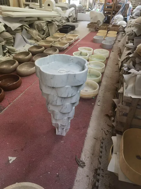 white stone sink, with a stone pedestal and fine veining, in a workshop