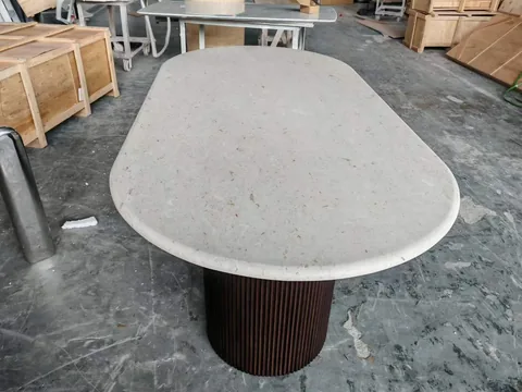 gray stone dining table, with a central pedestal base and a speckled texture, in a workshop