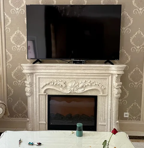 White Volakas marble fireplace surround, with carved scrollwork and fine veining, in a furnished room