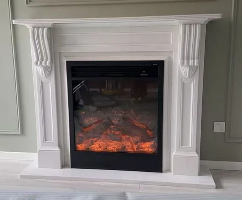 White Volakas marble fireplace surround, with a plain surface, in a furnished room