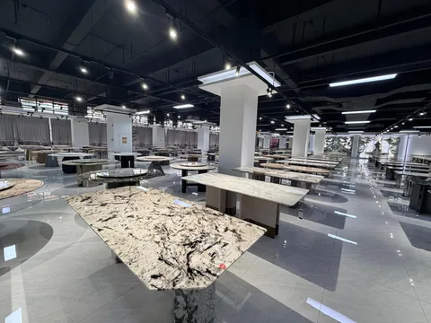 cream-beige stone dining table, with bold veining and a reflective finish, in a showroom