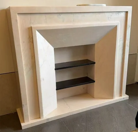 White Volakas marble fireplace surround, with fine veining and a soft satin finish, in a showroom