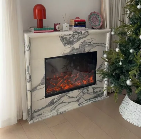 Arabescato Corchia marble fireplace surround, with bold veining, in a furnished room