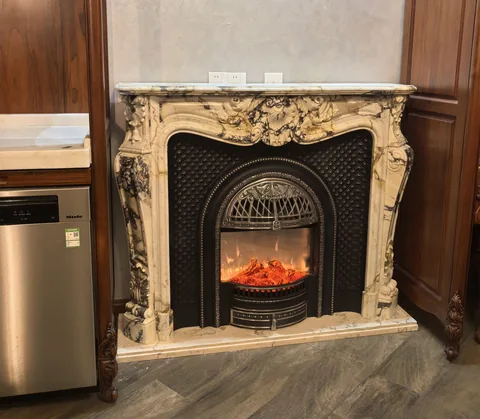White Volakas marble fireplace surround, with carved scrollwork and bold veining, in a showroom