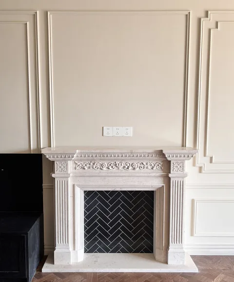 White Volakas marble fireplace surround, with a plain surface, in a furnished room