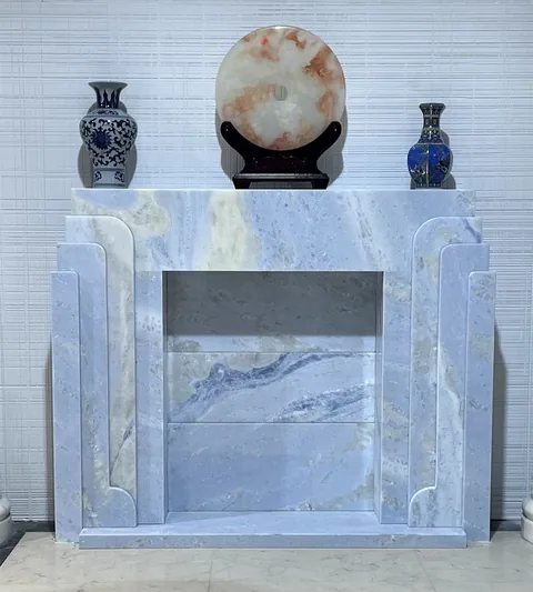 White Volakas marble fireplace surround, with stepped tiers and cloudy mottling, against a pale background