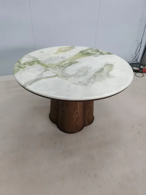 white stone coffee table, with a round top and bold veining, in a workshop