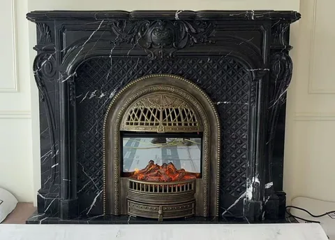 White Volakas marble fireplace surround, with an arched opening and fine veining, in a furnished room
