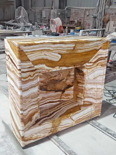 gold stone console table, with banded onyx-like striping and a reflective finish, in a workshop