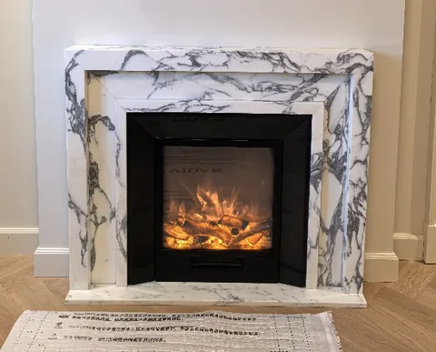 Arabescato Corchia marble fireplace surround, with stepped tiers and bold veining, in a furnished room