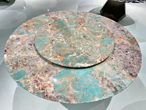green stone dining table, with a round top and a crystalline texture, in a showroom