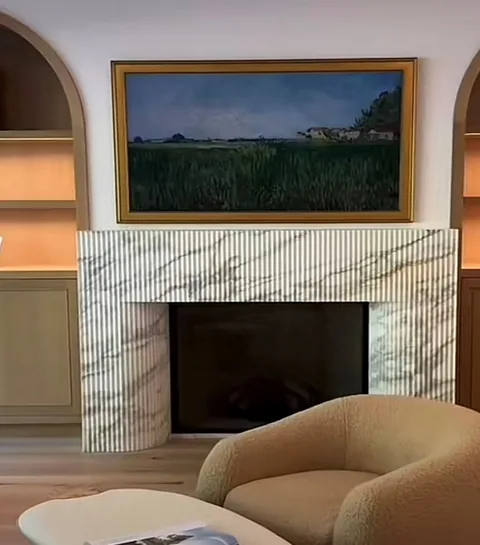 Arabescato Corchia marble fireplace surround, with a straight recessed opening and fine veining, in a furnished room
