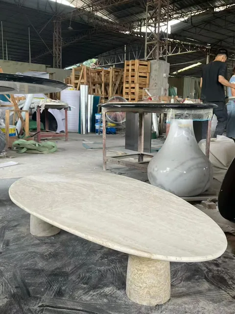 cream-beige stone coffee table, with twin supporting bases and cloudy mottling, in a workshop