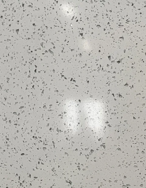 gray engineered stone slab, with a speckled texture and a reflective finish, in a close surface view