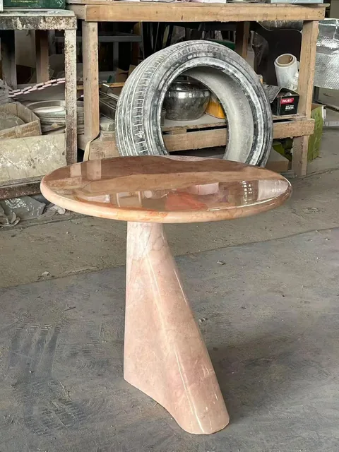rose-red stone side table, with cloudy mottling and a reflective finish, in a workshop