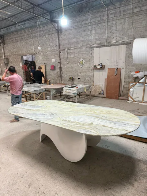 white stone dining table, with fine veining and a reflective finish, in a workshop