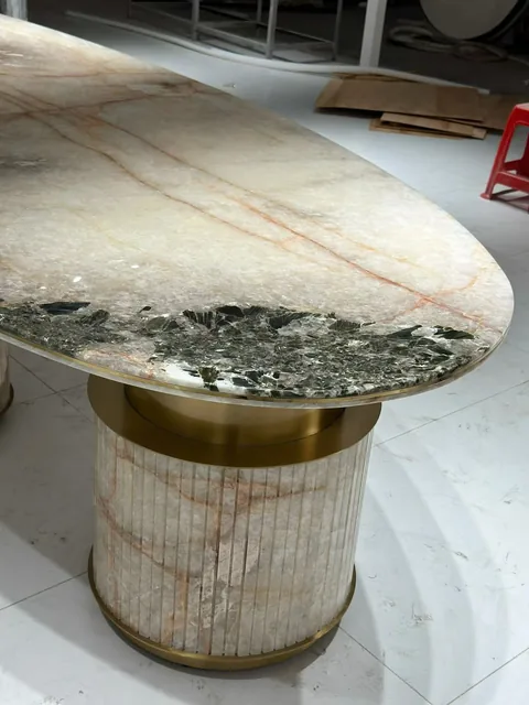 cream-beige stone dining table, with angular breccia fragments and a reflective finish, in a workshop