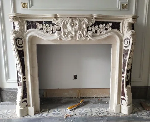 White Volakas marble fireplace surround, with carved scrollwork and bold veining, in a workshop