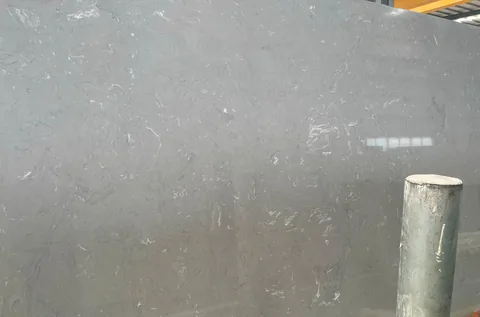 gray engineered stone slab, with a broad slab face and cloudy mottling, near workshop equipment
