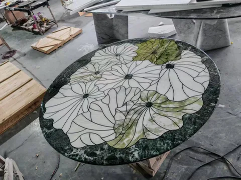green stone dining table, with a round top and cloudy mottling, in a workshop