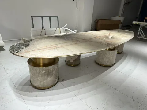 cream-beige stone dining table, with an oval top and fine veining, in a workshop