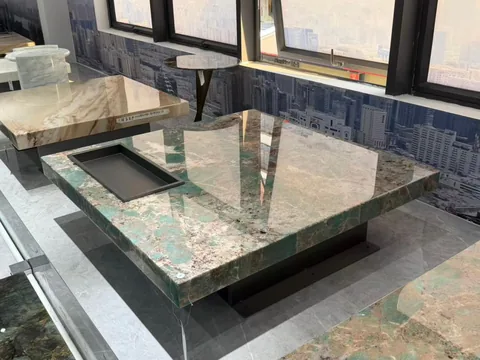 green stone coffee table, with a solid block base and cloudy mottling, in a showroom