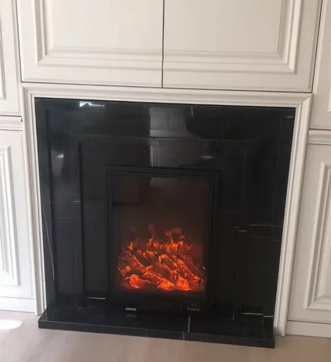 White Volakas marble fireplace surround, with a plain surface and a reflective finish, in a furnished room