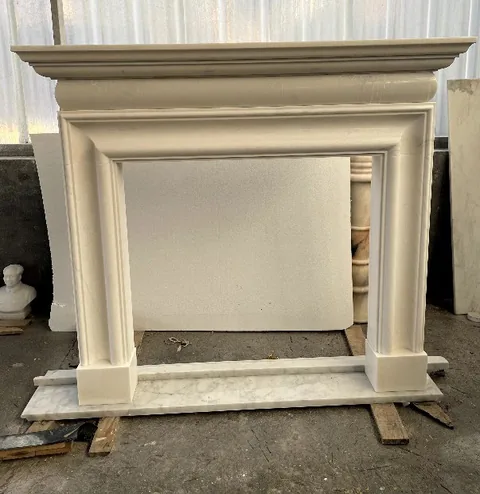 White Volakas marble fireplace surround, with stepped tiers and fine veining, in a workshop