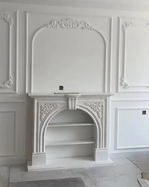 White Volakas marble fireplace surround, with an arched opening and a plain surface, against a pale background