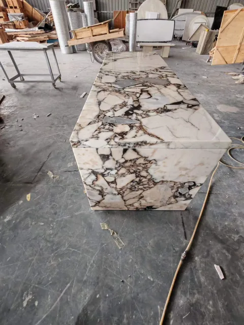 cream-beige stone countertop, with angular breccia fragments and a reflective finish, in a workshop
