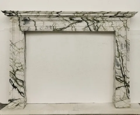 White Volakas marble fireplace surround, with bold veining, on a plain backdrop