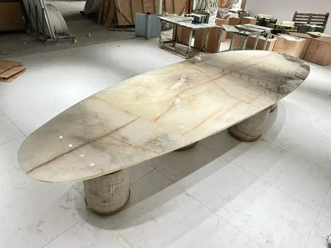 cream-beige stone dining table, with fine veining and a reflective finish, in a workshop